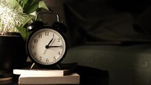 The Alarm Clock Is On The Night Table In The Bed Room With Plant Pot On A Book. And The Man Who Slept In Bed All Night Until Morning. The Clock Shows The Time From Night Until Morning. Timelapse. 4k