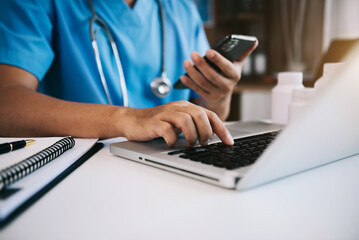 Medical Technology Concepts, The doctor is working on a smartphone and stethoscope and a digital laptop computer in a modern office in the morning at the desk.