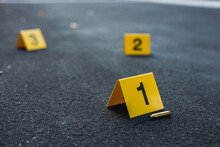 A Group Of Yellow Crime Scene Evidence Markers On The Street After A Gun Shooting Brass Bullet Shell Casing Rifle
