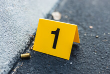 One Yellow Crime Scene Evidence Marker On The Street After A Gun Shooting Brass Bullet Shell Casing 9mm Handgun Pistol