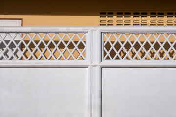 Wall Mural - Front view of white concrete fence wall with rhombus ventilation block beside beige house