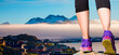 Woman walking sport feet on trail healthy lifestyle fitness - A layer of fog spreads between the mountains and the sea -Picturesque village and Colorful houses on coast of Greenland - Tasiilaq