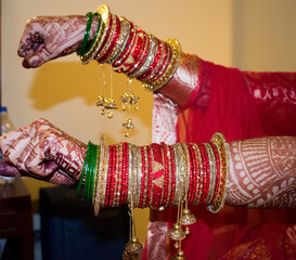 Indian bride hand showing beautiful bangles and heena. Selective focus on one hand.