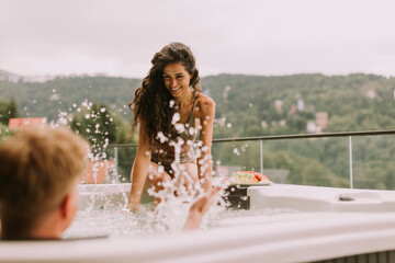 Young couple enjoying in outdoor hot tub on vacation