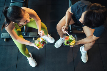 top view asian man and woman healthy eating salad after exercise at fitness gym. asian couple eating