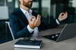 © Prostock-studio - Relaxed businessman meditating at workplace in office, calm male entrepreneur in suit sitting at desk, selective focus