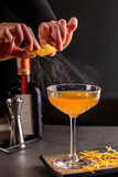 Fototapeta  - Professional female bartender flavoring a luxury cocktail with impressively spray from citrus peel. Cocktail zest shoot