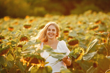 Wall Mural - Blonde in a white blouse in a sunflowers field