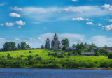 Fototapeta  - Arkhangelsk region, the village of Turchasovo near the Onega River. the old wooden Church of the Transfiguration of 1786 and the bell tower of 1793. View of ancient architecture across the river