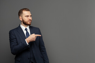 Wall Mural - Portrait of cheerful excited joyful satisfied handsome attractive businessman dressed in formal outfit pointing on empty blank copy space isolated on gray background