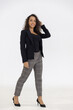 © Danai - Portrait of smart caucasian businesswoman with curly hair in black jacket suite with trousers smiling standing posing isolate on white background, vertical full body studio shot