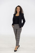 © Danai - Portrait of smart caucasian businesswoman with curly hair in black jacket suite with trousers smiling hands in pocket isolate on white background, vertical full body studio shot