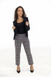 © Danai - Portrait of smart caucasian businesswoman with curly hair in black jacket suite with trousers smiling standing posing isolate on white background, vertical full body studio shot
