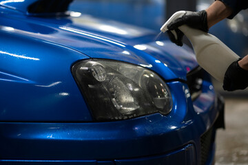 Wall Mural - male detailer doing work on the car, cleaning machine and applying spray on the surface