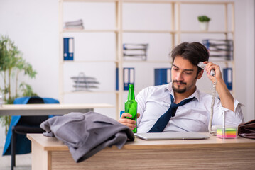 Poster - Young alcohol addicted employee sitting in the office