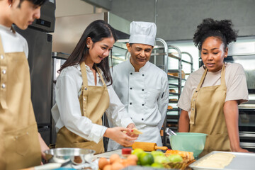 Wall Mural - Students In Cookery Class Mixing Ingredients For Recipe In Kitchen.Male And Female young  Students With chef Teacher Preparing Ingredients For Dish In Kitchen Cookery Class.