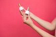 © Yuliia Sukharieva - Female's hands holding bottles nail polish on pink background.