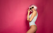 © lashkhidzetim - Beautiful Sexy  girl standing on pink background in a colours bathing suit bikini and smiling. Pink hair.