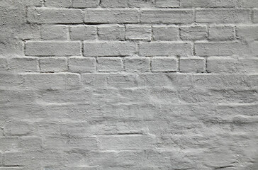 Grey wall, texture, background. The building wall, painted with whiting. Wavy and bumpy surface. Gray brick wall in gray old-style color. Uneven brickwork. Rough whitewashed wall surface