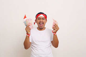 Poster - Happy asian man standing while holding indonesian money. Celebrating Independence day concept