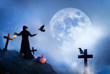 The Sorcerer And Birds In The Cemetery At The Moon. Mystical Image. Halloween.