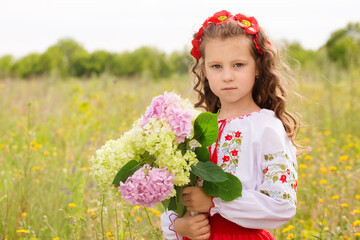 Wall Mural - A girl in a Ukrainian costume in a field with a bouquet