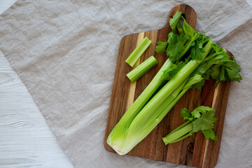 Raw Organic Celery on a wooden board, top view. Flat lay, overhead, from above. Copy space.