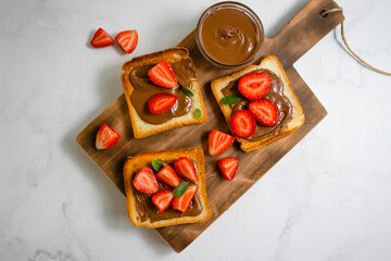 Wall Mural - Bread with chocolate paste, strawberries on a light background