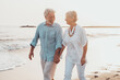 © Daniel - Couple of old mature people walking on the sand together and having fun on the sand of the beach enjoying and living the moment. Two cute seniors in love having fun. Barefoot walking on the water.