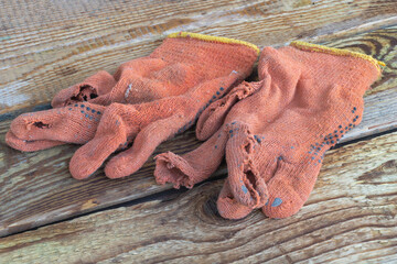 Some used and torn construction gloves on a wooden background