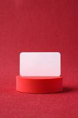 Poster - blank business card on pedestal on vivid red background studio