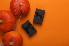 Halloween Background. Black Gift Boxes And Pumpkins In A Web With A Spider On An Orange Background. Happy Halloween