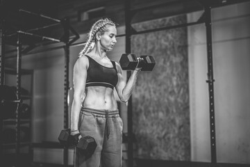 Wall Mural - Muscular attractive woman training biceps with dumbbells in her hands, functional gym, weights training.