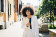 © Westend61 - Smiling Afro businesswoman holding laptop in city on sunny day