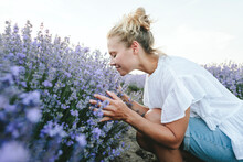 Happy Woman Smelling Lavender Plants In Field
