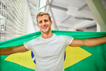 Smiling Man Holding Brazil Flag At Sports Event In Stadium
