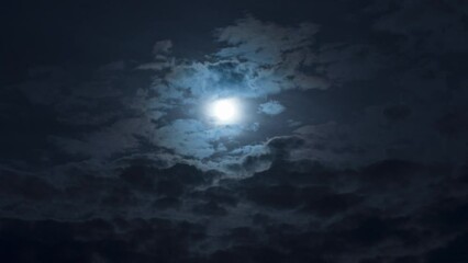 Wall Mural - a mysterious night sky with clouds and a full moon. nighttime timelapse. clouds cover and reveal the