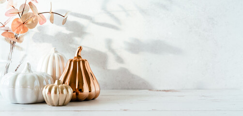 Details of Still life, pumpkins, candle, brunch with leaves on white table background, home decor in a cozy house. Autumn weekend concept. Fallen leaves and home decoration