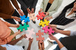 © Studio Romantic - Closeup top view of diverse businesspeople connect jigsaw puzzle pieces motivated for shared business goal or success. Employees engaged in teambuilding activity at company training or meeting.