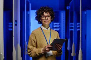 portrait of female engineer in eyeglasses looking at camera while working on digital tablet in serve