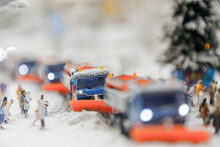 Layout Of The City And Small Figures. Snow-covered Road On Which Snowplows Move