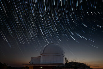 astronomical observatory under star trails sky at night