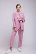 © SBekhinov - Fashion photo of a beautiful elegant young woman in a pretty soft pink oversized suit, jacket, pants, sneakers posing over white, soft gray background. Studio Shot.