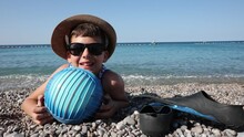 Happy Boy Has Water Polo Ball On The Beach. Looking At Camera. Concept Of Travel, Tourism, Family.