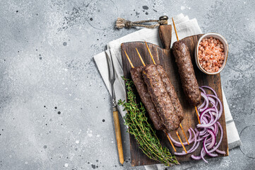 Wall Mural - Grilled kofta kofte shish kebab from mince lamb and beef meat on Skewer. Gray background. Top view. Copy space