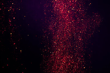 Abstract dark bokeh background of small purple festive glitter lights dust particles