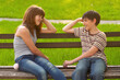 Smiling teenage boy and girl sitting on the bench in the summer park 