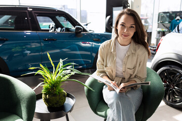 Wall Mural - young happy woman in new car dealership showroom