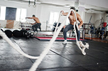 Fit And Muscular Arabian Man Working Out With Heavy Ropes In Gym.