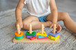 © dtatiana - Cute caucasian little girl playing on the floor at home with eco wooden toys. Montessori toy. The child playing educational games.